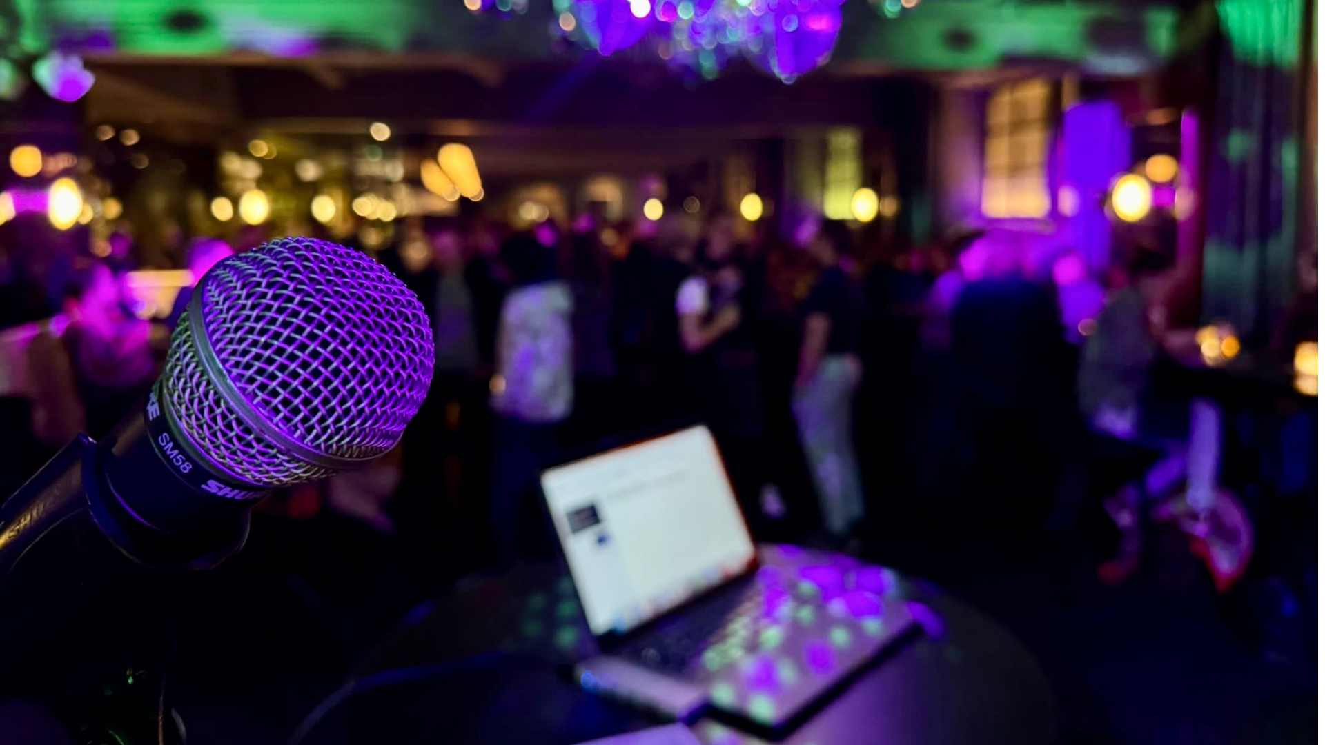 Picture of a microphone in the foreground and blurred out people in the background